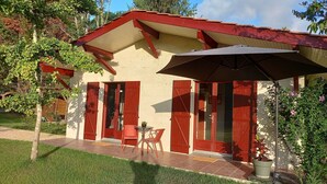 Une maison avec un toit rouge, un patio couvert avec une table et des chaises, et une plante en pot.