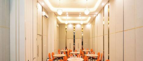 A conference room with multiple tables and orange chairs, equipped with water bottles and glasses.