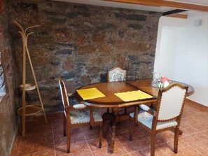 Un espace repas avec un mur en pierre, une table en bois et des chaises.