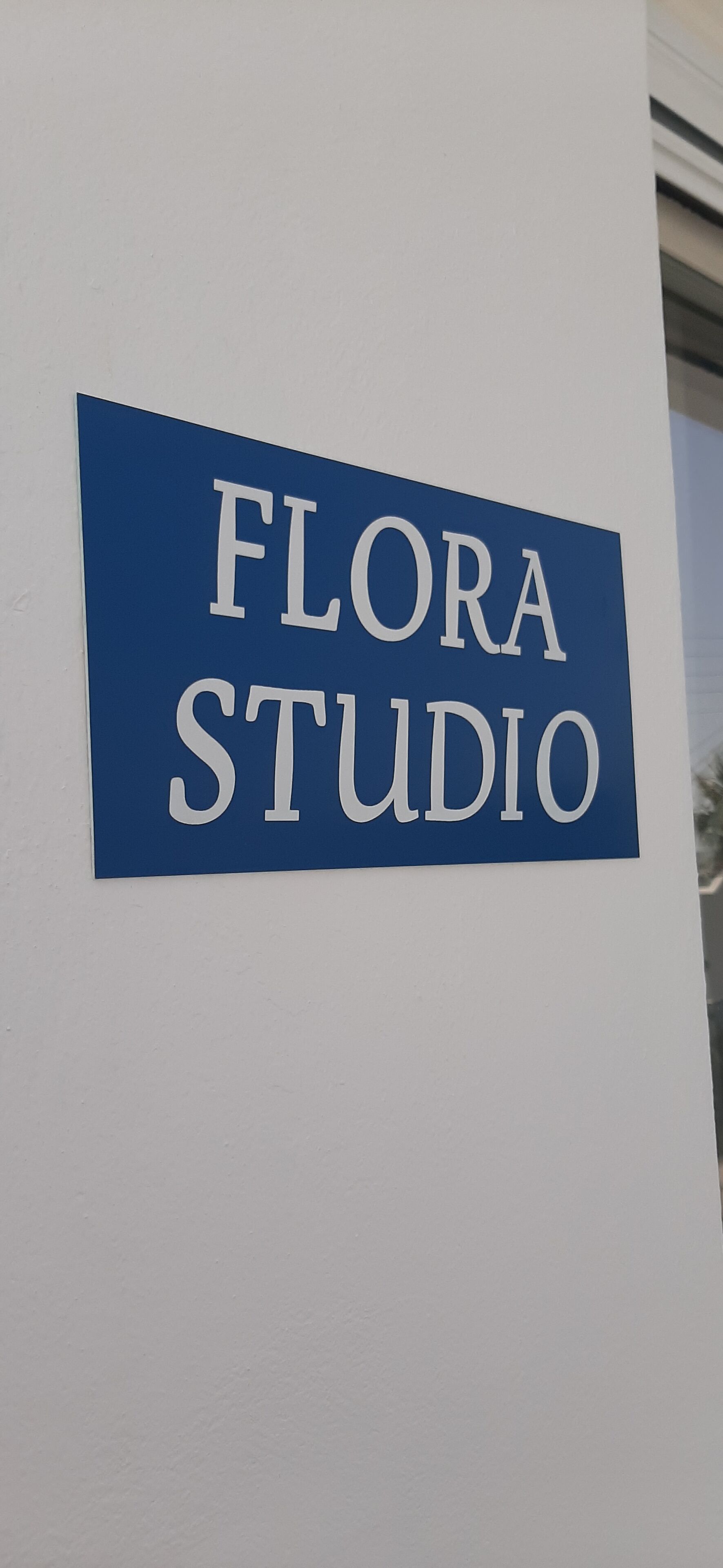 A sign with the text "FLORA STUDIO" on a white wall.