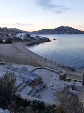 A coastal landscape with a stone pathway leading to a beach, white buildings, and a calm sea. - studios FLORA in naoussa paros (Naousa Paros)