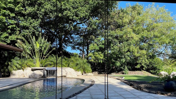 Un conjunto de columpios en un área ajardinada con una piscina y un campo de golf al fondo.
