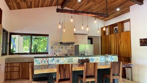 Una cocina con armarios de madera, un salpicadero de azulejos y una isla central con taburetes de bar.
