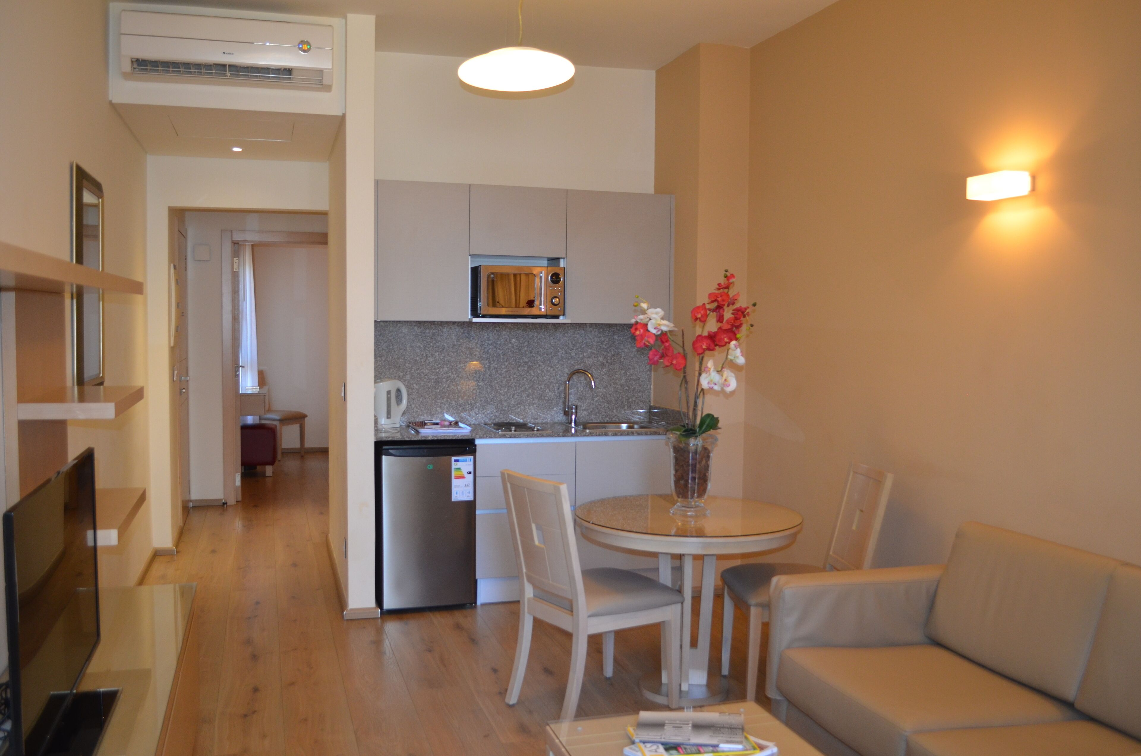 A compact living space with a kitchenette, a dining area with a table and chairs, and a sofa.