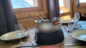 A dining table set with plates, cutlery, and glasses, with a view of a snowy mountain through a window.