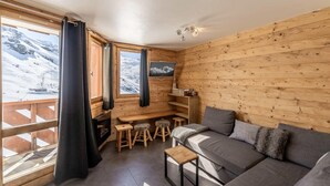 A cozy cabin with a wooden interior, a sofa, a small table, and a TV.