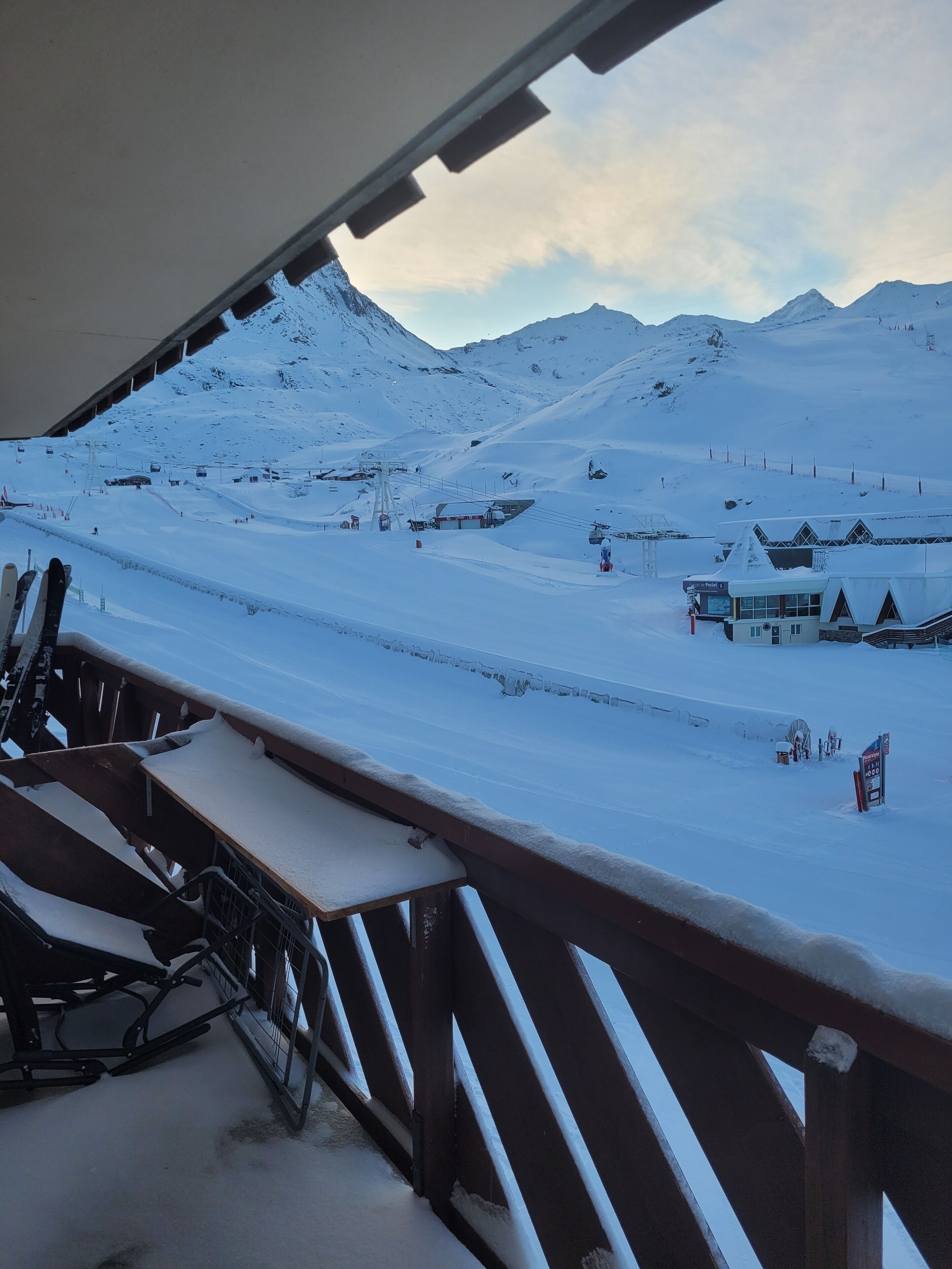 A snow-covered mountain landscape with a ski lift and buildings in the background.