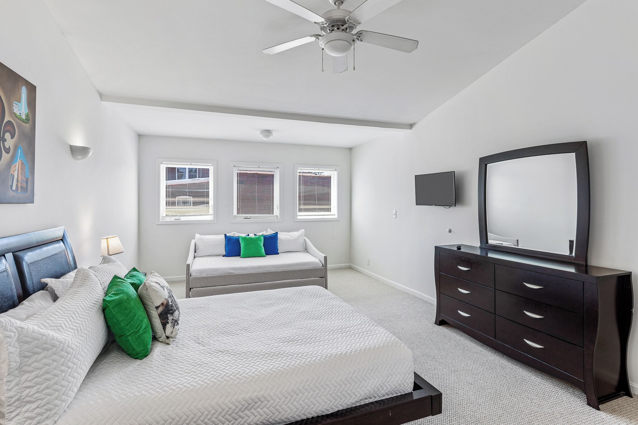 Ein Schlafzimmer mit Bett, Kommode, Fernseher und Deckenventilator.