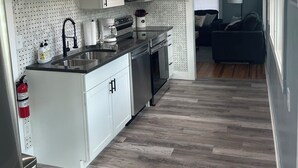 Una cocina moderna con armarios blancos, electrodomésticos de acero inoxidable y piso de madera en espiga.