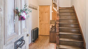 A wooden staircase with a handrail, a wooden door with a brass handle, and a radiator on the floor.