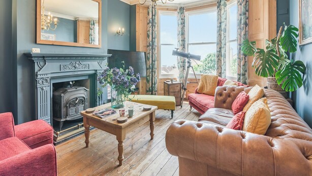 A living room with a fireplace, a large mirror, a chandelier, and a comfortable sofa.