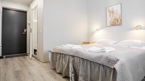 Une chambre d’hôtel moderne avec un grand lit, une porte et un luminaire fixé au mur.