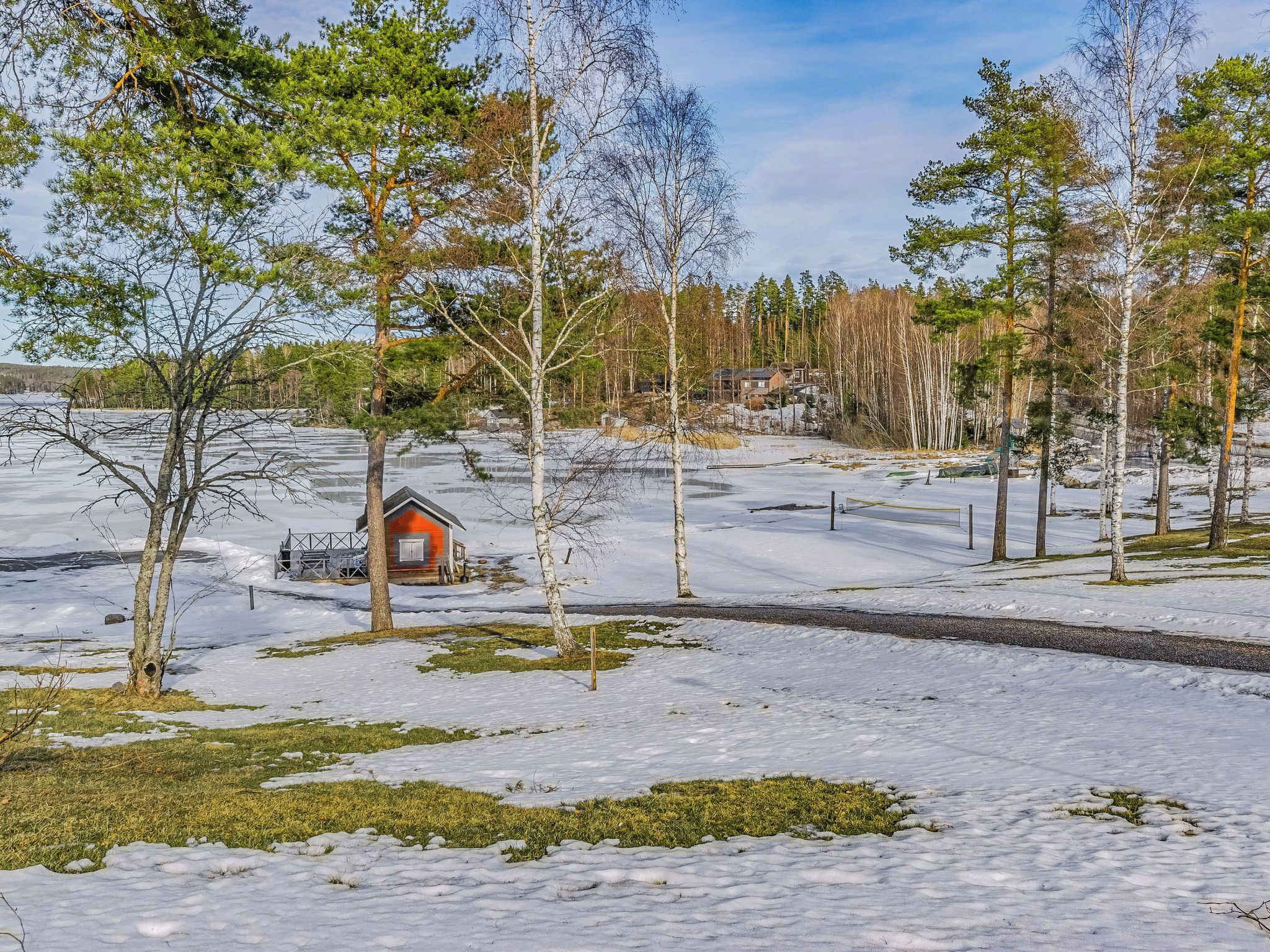 A snow-covered landscape with a small cabin, trees, and a clear sky.