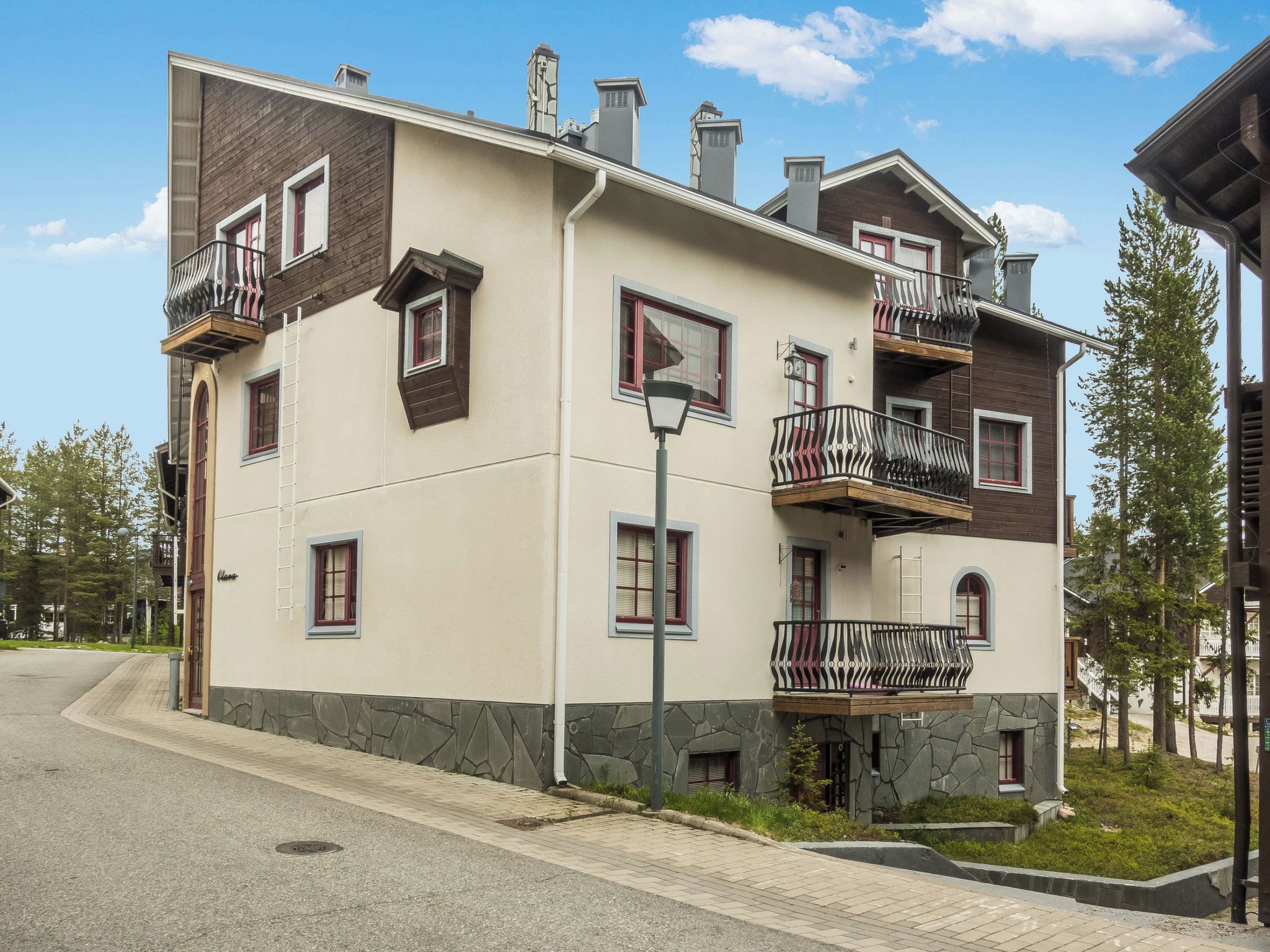Un edifici residencial de diversos pisos amb balcons, façana de pedra i cel blau.
