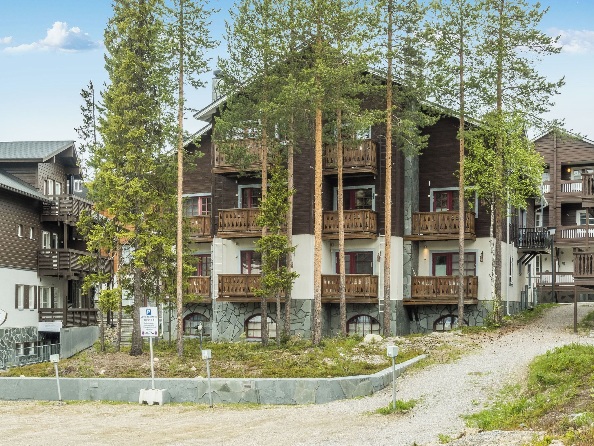 A multi-story building with balconies, surrounded by trees.