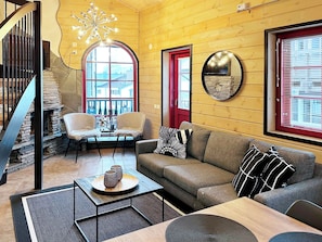 A cozy living room with a stone staircase, a wooden ceiling, a round mirror, and a red door. - Levin otava 8 by Interhome (Kittilä)