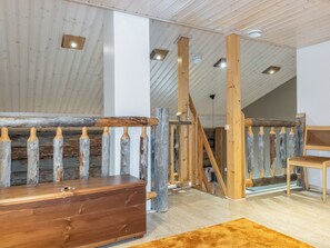 Una habitación con un banco de madera, un techo alto con vigas a la vista y una escalera con barandillas de madera.