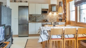Une cuisine de taille réduite équipée d’un réfrigérateur, d’une cuisinière, d’un four à micro-ondes et de meubles de rangement en bois.