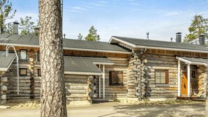 Une cabane en rondins avec une cheminée en pierre, une porte en bois et une fenêtre avec des volets.
