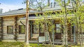 Une cabane en rondins avec un porche, de nombreuses fenêtres et une cheminée.