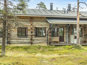 A log cabin with a porch, windows, and a chimney.