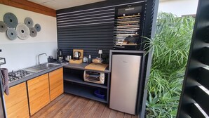 Een compacte keuken met een inbouwoven, koffiezetapparaat en een spoelbak.