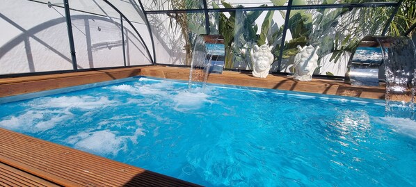 A swimming pool with a wooden deck and decorative statues.