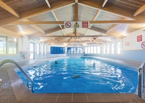Een binnenzwembad met houten plafond en duidelijke borden met een waterdiepte van 1,3 meter.