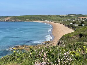 A coastal landscape with a sandy beach, grassy hills, and a clear sky. - Pottsville Cabin - Short Walk to Praa Sands Beach (Penzance)