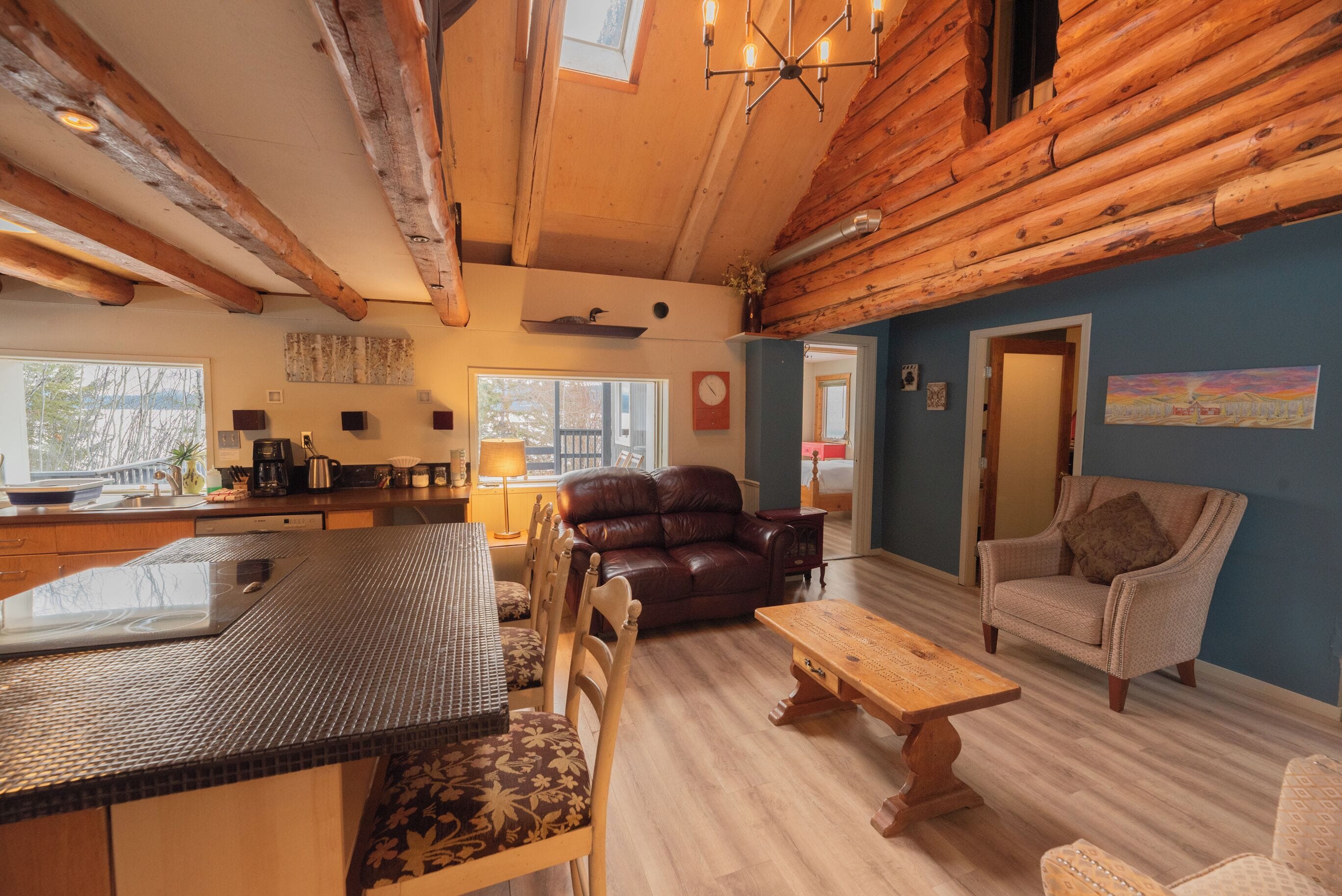Interior rústico de una cabaña con cocina, comedor y zona de estar.