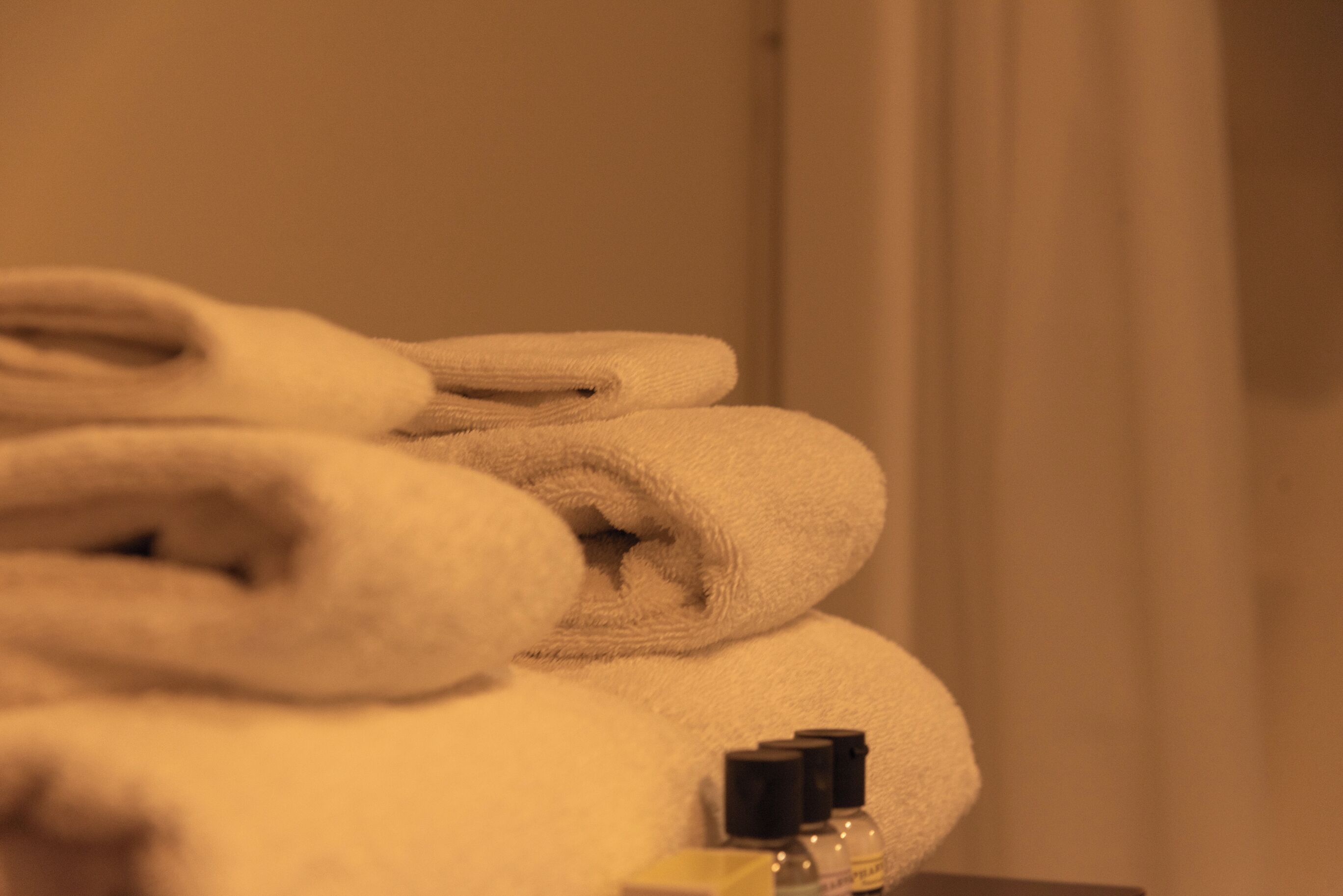 A stack of folded towels and a bottle of lotion on a surface.