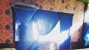 A room with two beds, a mosquito net, and patterned wallpaper. - Iquitos (San Juan Bautista)