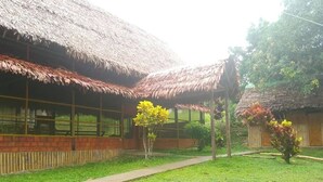 A building with a thatched roof and large windows, surrounded by a well-maintained lawn and a pathway. - Iquitos (San Juan Bautista)