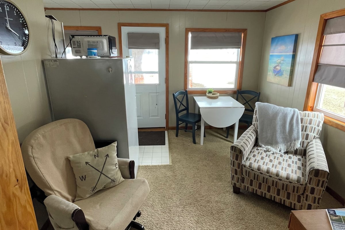 A compact living space with a kitchenette, a dining area, and a seating area with a patterned armchair and a recliner.