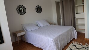 A bedroom with a bed, nightstands, a wardrobe, and two wall decorations.