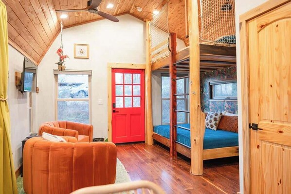 A cozy room with a red door, a bunk bed, a sofa, and a wooden ceiling. - Artsy Chattanooga Tiny Cabin Next to State Forest (Chattanooga)