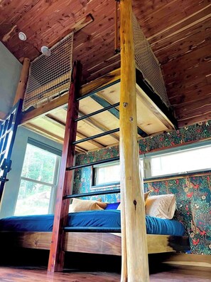 A bunk bed with a wooden ladder, a window with a view of greenery, and a patterned wall. - Artsy Chattanooga Tiny Cabin Next to State Forest (Chattanooga)
