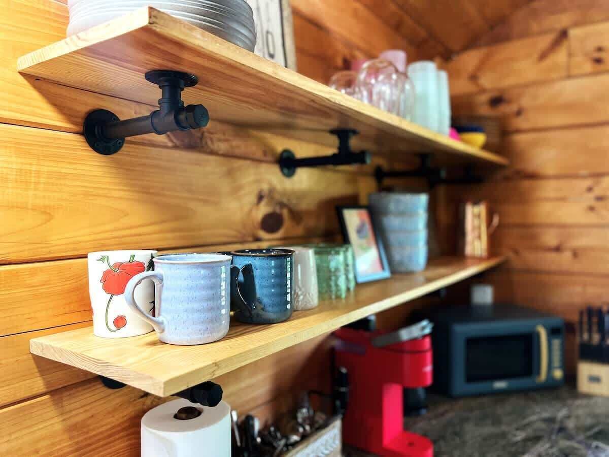 Ein Holzboden mit verschiedenen Tassen und einer Mikrowelle in rustikalem Ambiente.