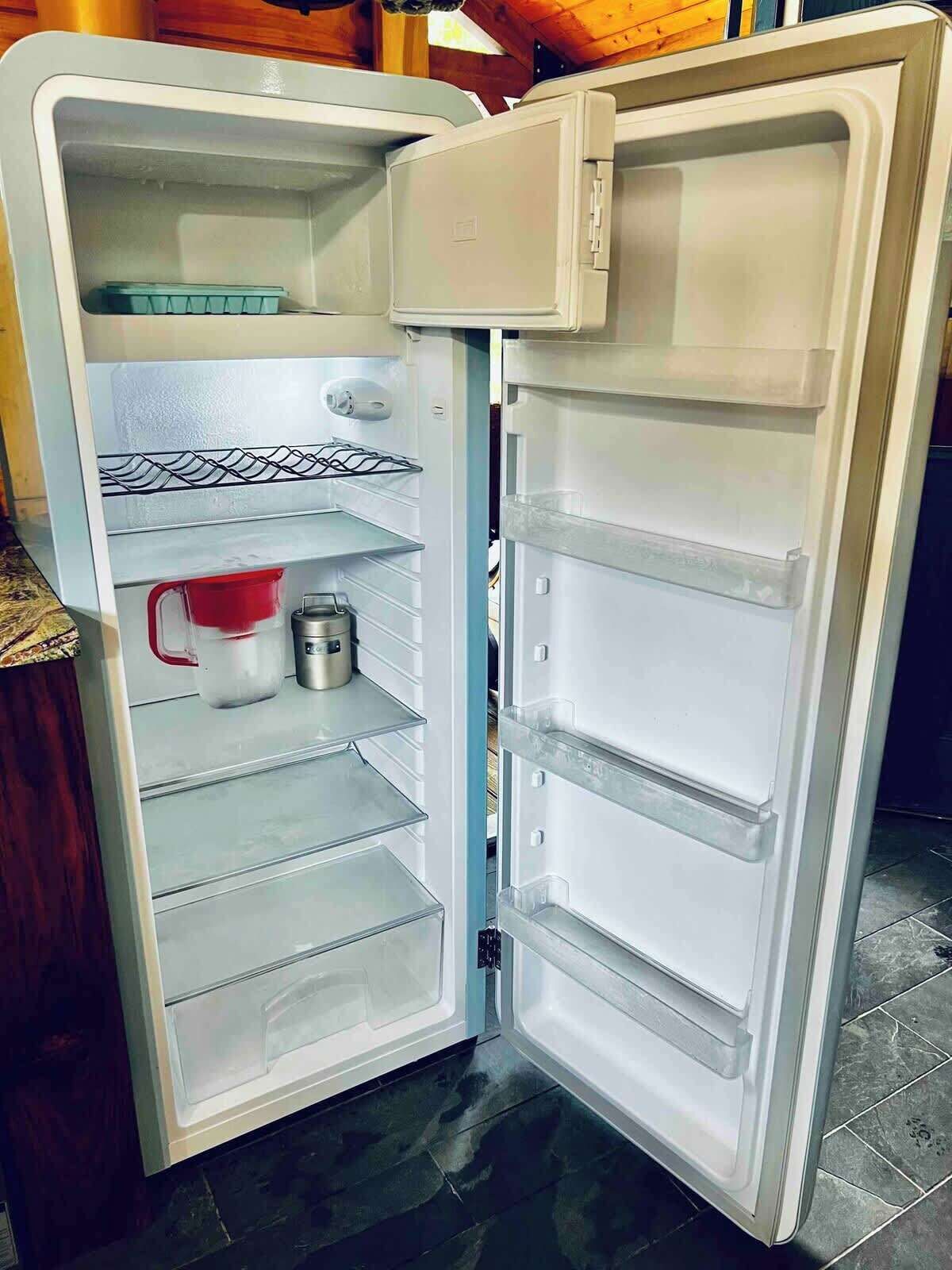 Un refrigerador abierto con varios estantes y un compartimento congelador.