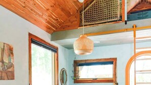 A cozy room with a wooden ceiling, a dining table with red chairs, a sofa, and a large window. - Whippoorwill: Cozy Mountain Escape w/ Stargazing Shower & Trails (Marion County)