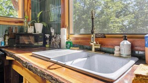 A kitchen with a sink, wooden countertop, and a window with a view of trees. - Whippoorwill: Cozy Mountain Escape w/ Stargazing Shower & Trails (Marion County)