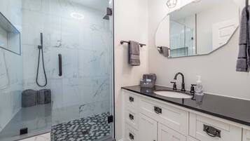 Une salle de bain moderne avec une douche à parois de verre, un meuble-lavabo et un grand miroir.