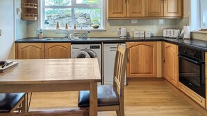 Una cucina con mobili in legno, una lavatrice, una lavastoviglie e un tavolo da pranzo con sedie.