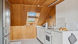 Une cuisine de taille réduite avec des murs en bois, une fenêtre et une vue sur l’extérieur.