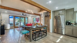 A spacious kitchen with wooden beams, a large stainless steel refrigerator, and a dining area with a bench and chairs. - Views! Private! Tranquil! Lakefront! Forest! Sunsets! Acreage! Docks! (Lower Lake)