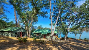 A cabin with a green roof, surrounded by trees and a lake. - Views! Private! Tranquil! Lakefront! Forest! Sunsets! Acreage! Docks! (Lower Lake)