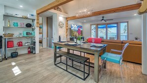 A modern kitchen with wooden beams, a dining table with chairs, and a view of the outdoors through large windows. - Views! Private! Tranquil! Lakefront! Forest! Sunsets! Acreage! Docks! (Lower Lake)