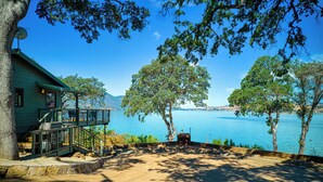 A cabin with a deck overlooking a lake, surrounded by trees. - Views! Private! Tranquil! Lakefront! Forest! Sunsets! Acreage! Docks! (Lower Lake)