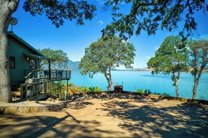 A cabin with a deck overlooking a lake, surrounded by trees. - Views! Private! Tranquil! Lakefront! Forest! Sunsets! Acreage! Docks! (Lower Lake)