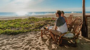 Two people sitting at a table with a view of the beach and ocean. - Dreamy Condo in Centro Histórico + Unlimited Pool Club Access! (Todos Santos)